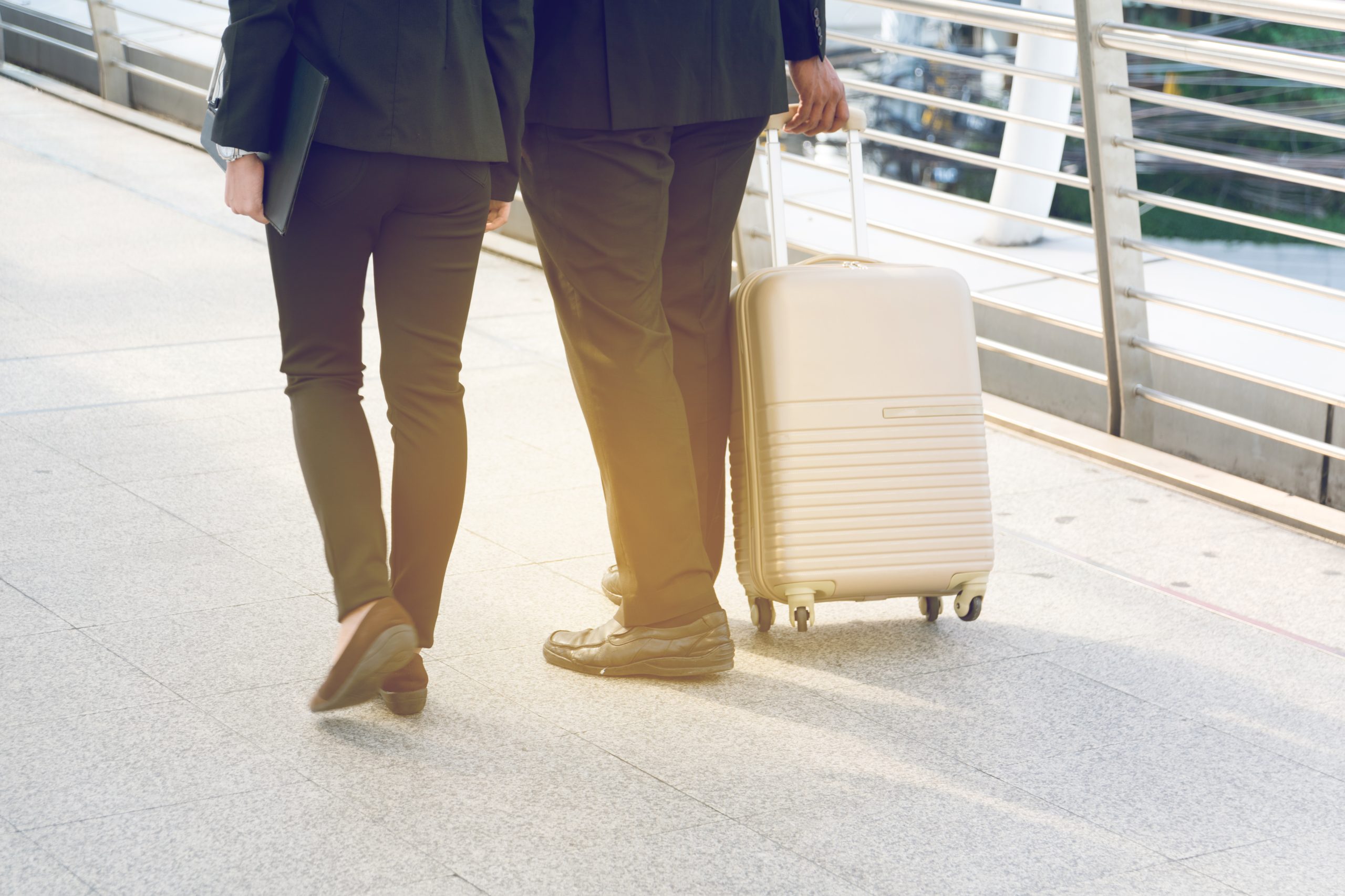 Businessman and Businesswoman pulling a suitcase in a big city.